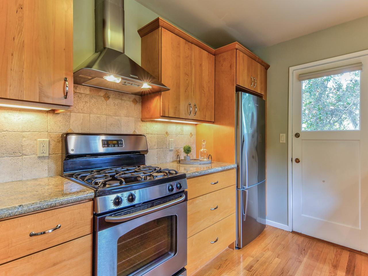 3 11th Avenue Carmel, CA 93923 - Photo 12 of 26 a kitchen with granite countertop a stove and a wooden cabinets