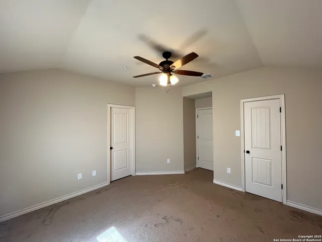 an empty room with closet and a ceiling fan