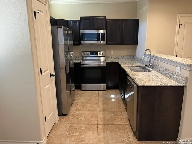 a kitchen with stainless steel appliances granite countertop a refrigerator and a stove top oven