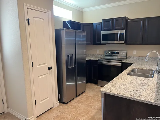 a kitchen with stainless steel appliances granite countertop a refrigerator and a stove top oven
