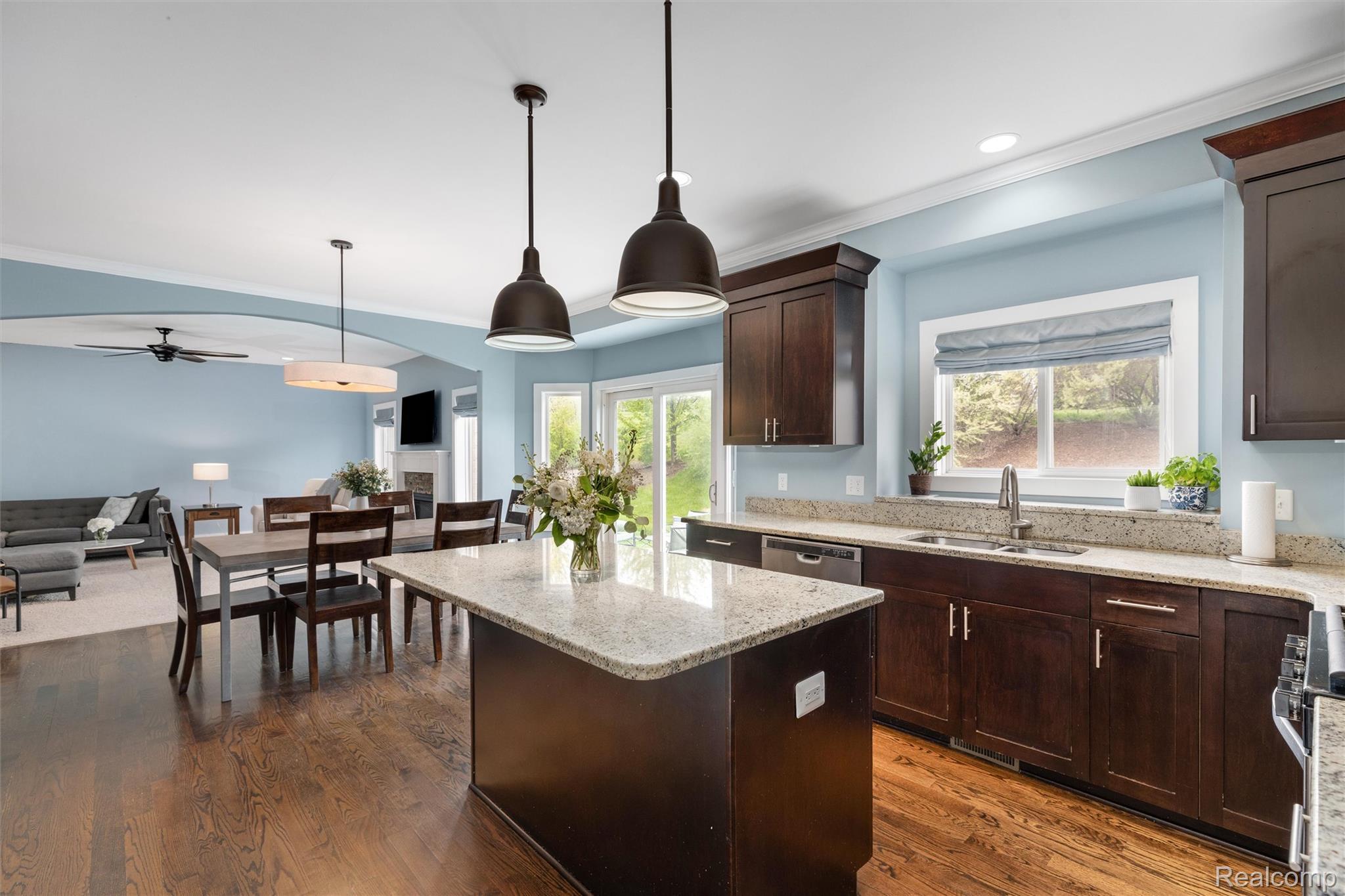 1016 West Snell Road Rochester, MI 48306 - Photo 16 of 35 Open-concept kitchen featuring an island with pendant lighting, dark wood cabinetry, and light-toned countertops