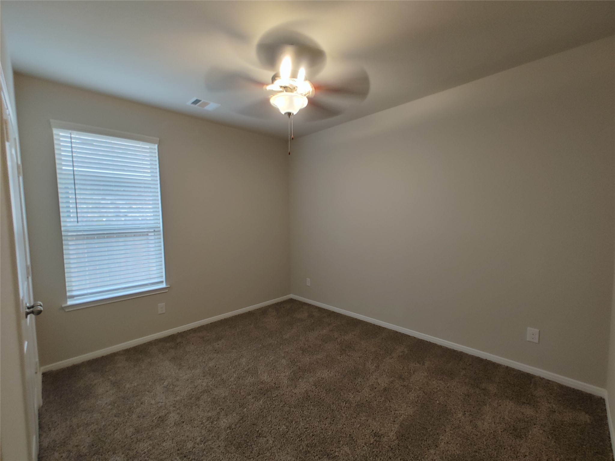 6206 Blue Coast Lane Conroe, TX 77304 - Photo 18 of 43 an empty room with a chandelier fan and windows