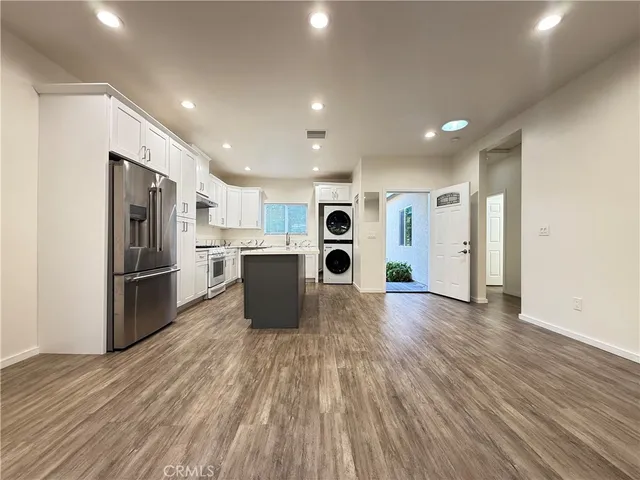 a view of kitchen with stainless steel appliances kitchen island wooden floors and refrigerator