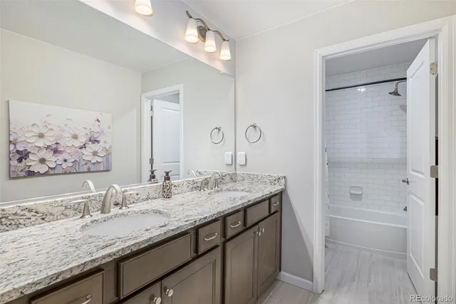 a bathroom with a granite countertop double vanity sink and mirror
