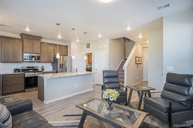 a living room with stainless steel appliances furniture and kitchen view