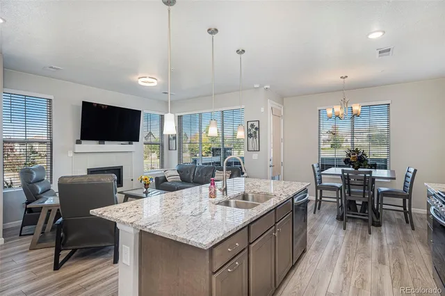 a open kitchen with stainless steel appliances granite countertop a kitchen island a dining table and chairs