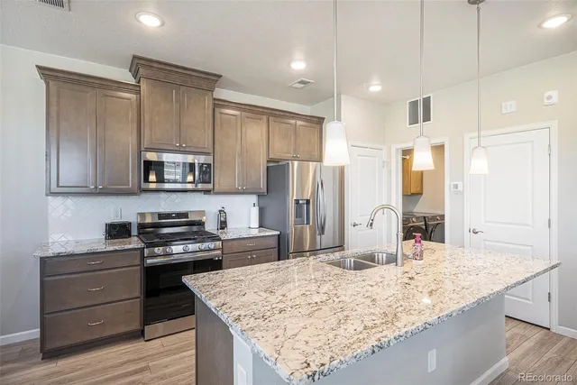 a kitchen with stainless steel appliances granite countertop a sink stove and refrigerator
