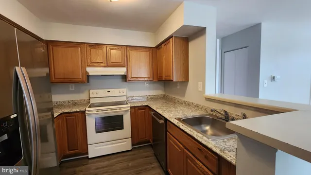 a kitchen with granite countertop stainless steel appliances a sink stove and refrigerator