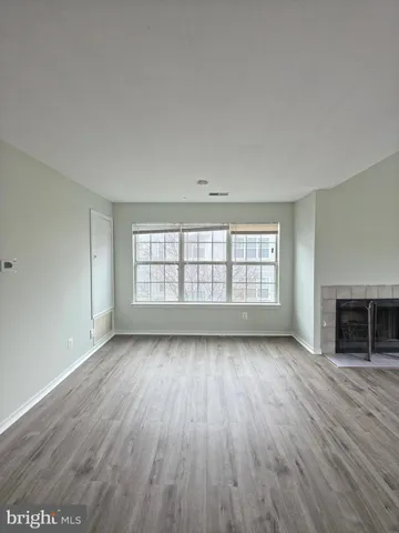 an empty room with wooden floor fireplace and windows