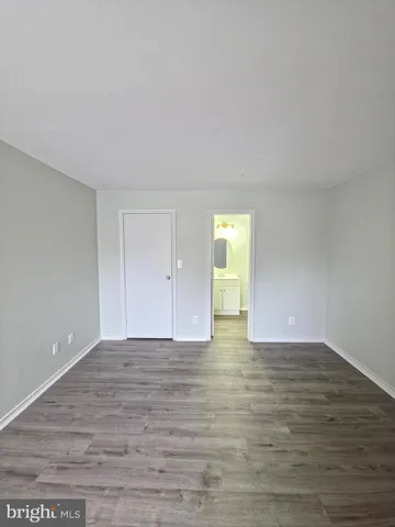 a view of an empty room with wooden floor and closet