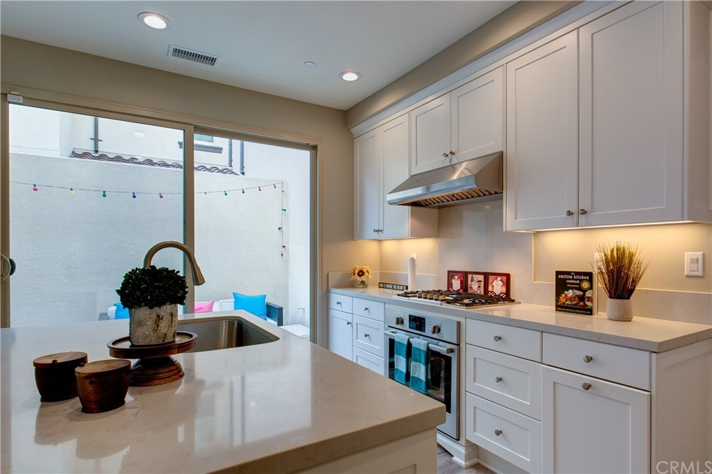 168 Outwest Irvine, CA 92618 - Photo 19 of 36 a kitchen with stainless steel appliances granite countertop a stove a sink dishwasher and white cabinets with wooden floor
