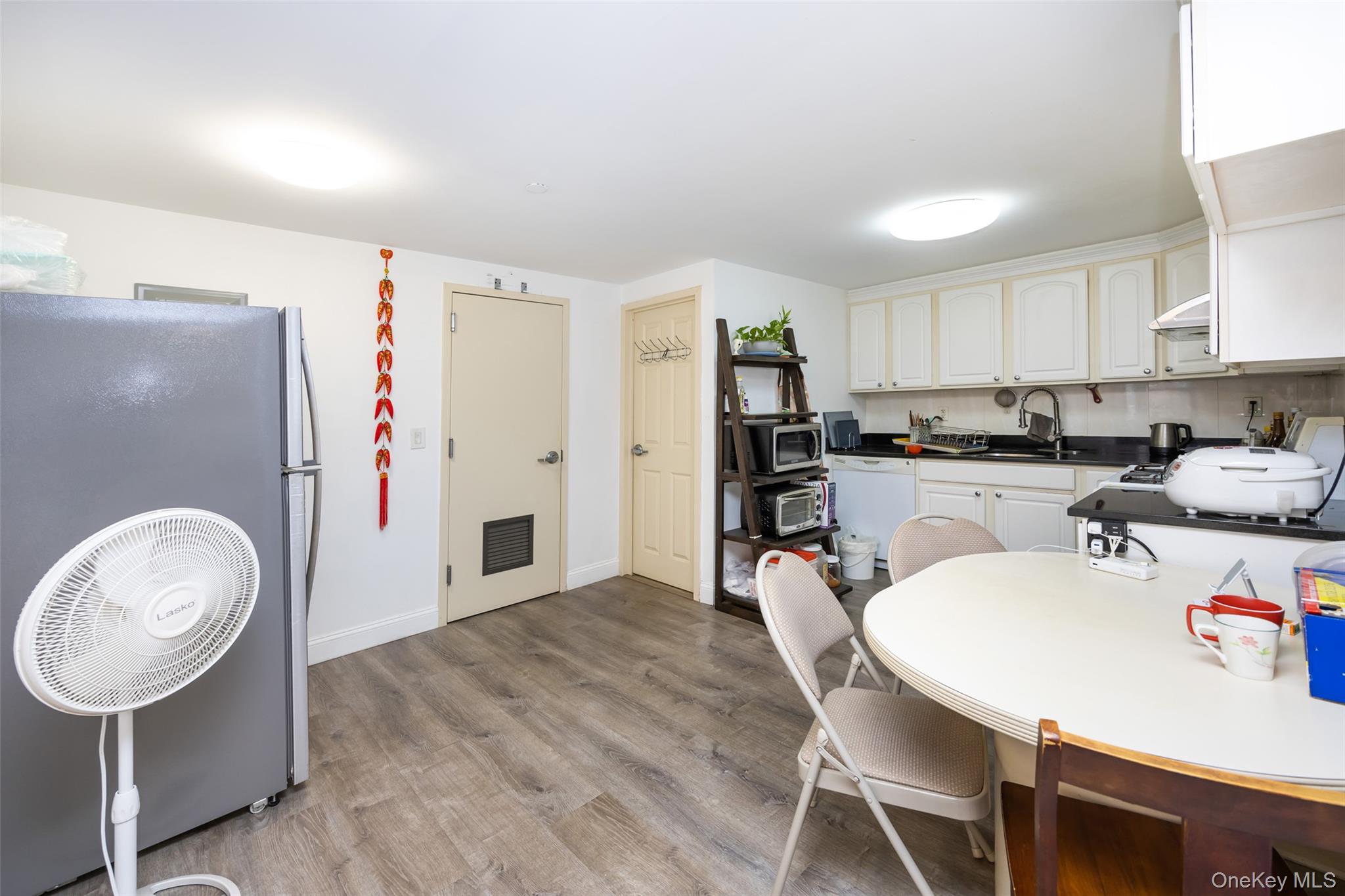 43-17 Union Street, Unit 4E Queens, NY 11355 - Photo 11 of 19 Kitchen featuring appliances with stainless steel finishes, dark countertops, light wood-type flooring, decorative backsplash, and white cabinets