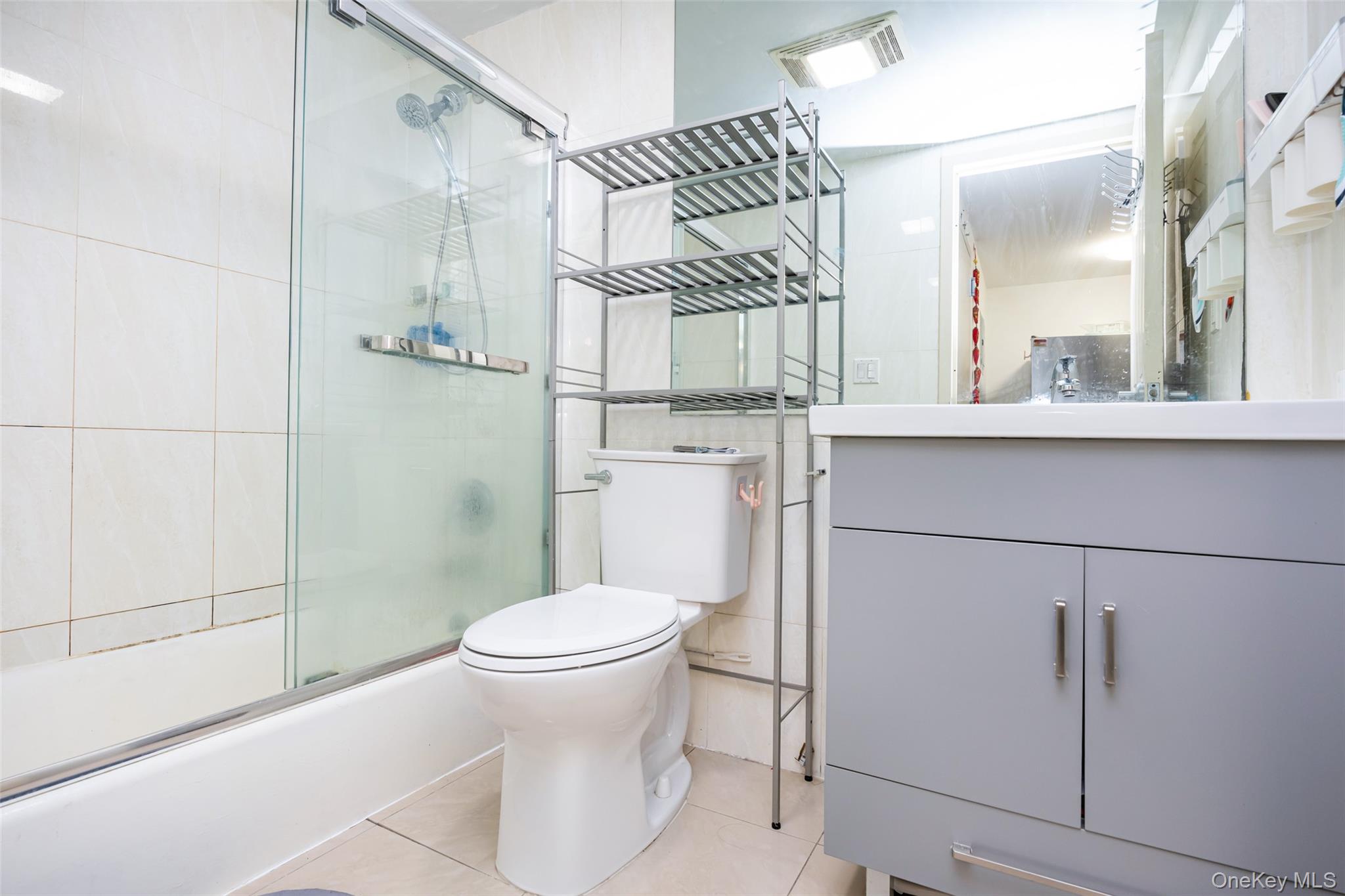 43-17 Union Street, Unit 4E Queens, NY 11355 - Photo 16 of 19 Bathroom with vanity, light tile patterned floors, and combined bath / shower with glass door