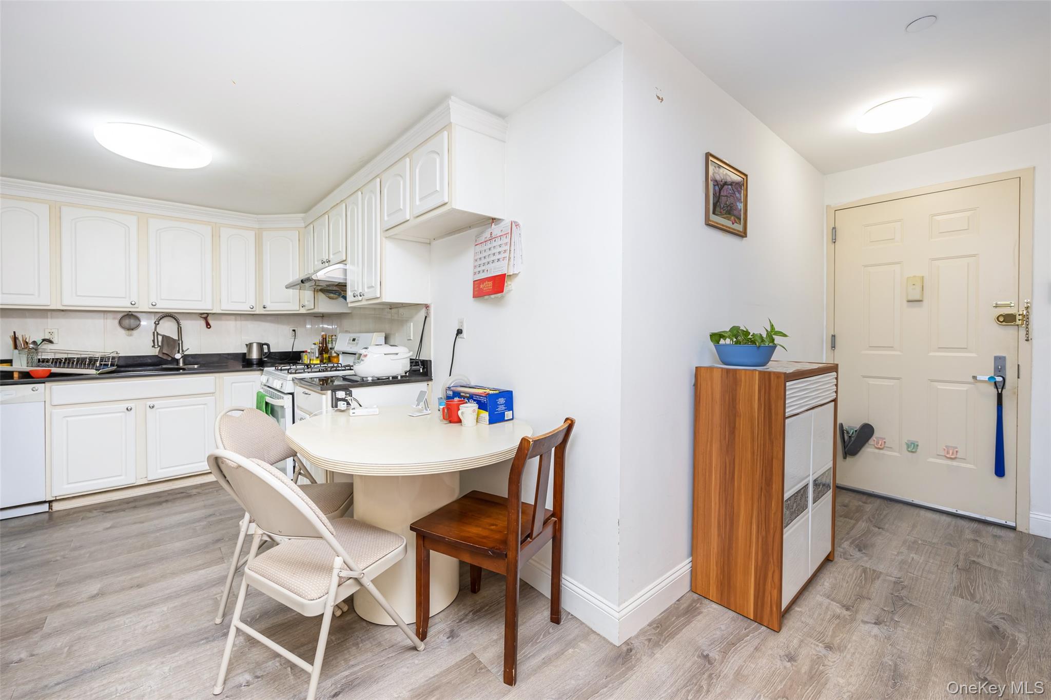 43-17 Union Street, Unit 4E Queens, NY 11355 - Photo 19 of 19 Kitchen with light wood-style flooring, dark countertops, white appliances, and white cabinetry