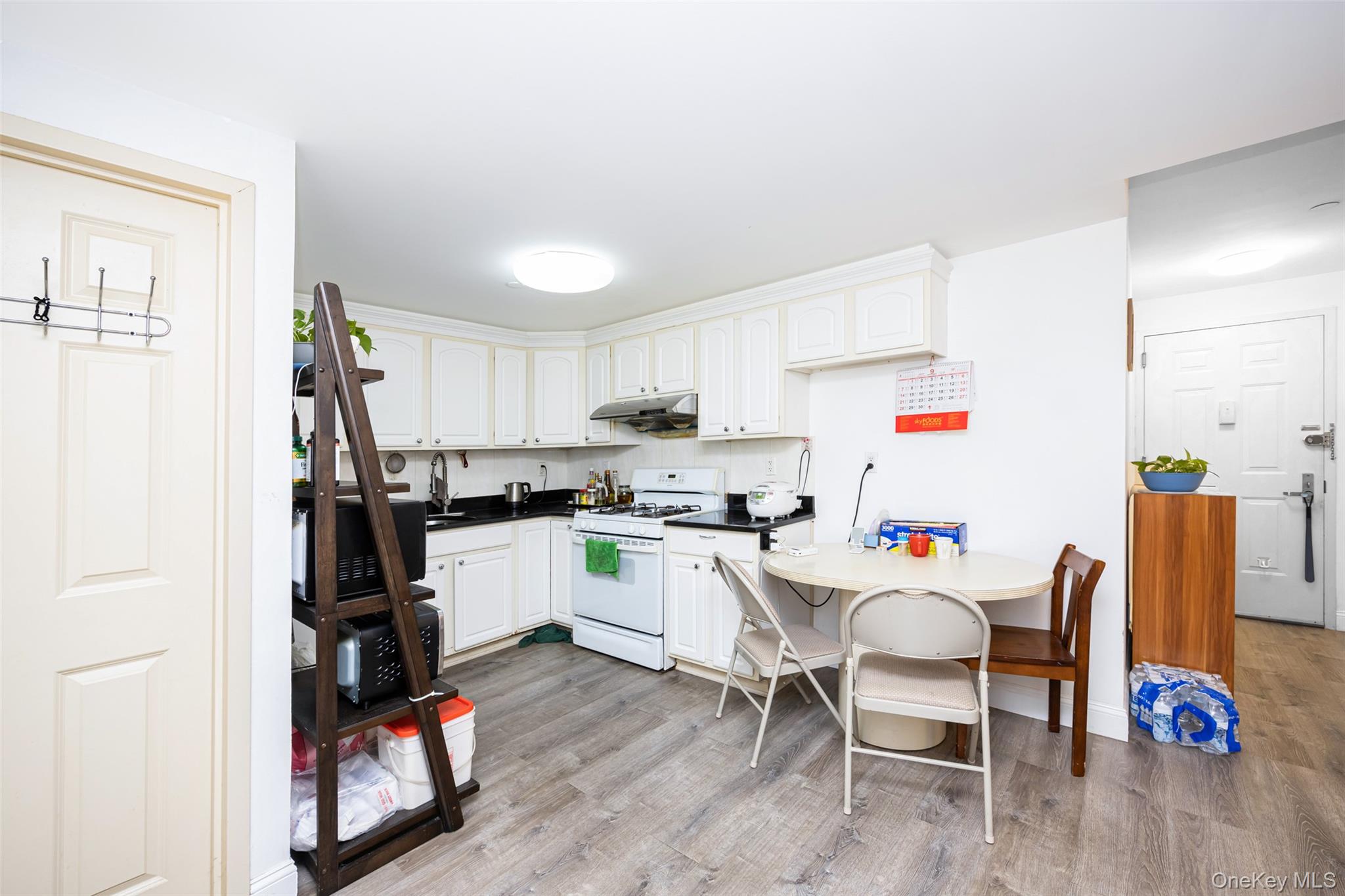 43-17 Union Street, Unit 4E Queens, NY 11355 - Photo 9 of 19 Kitchen with dark countertops, white gas range oven, white cabinetry, and light wood finished floors