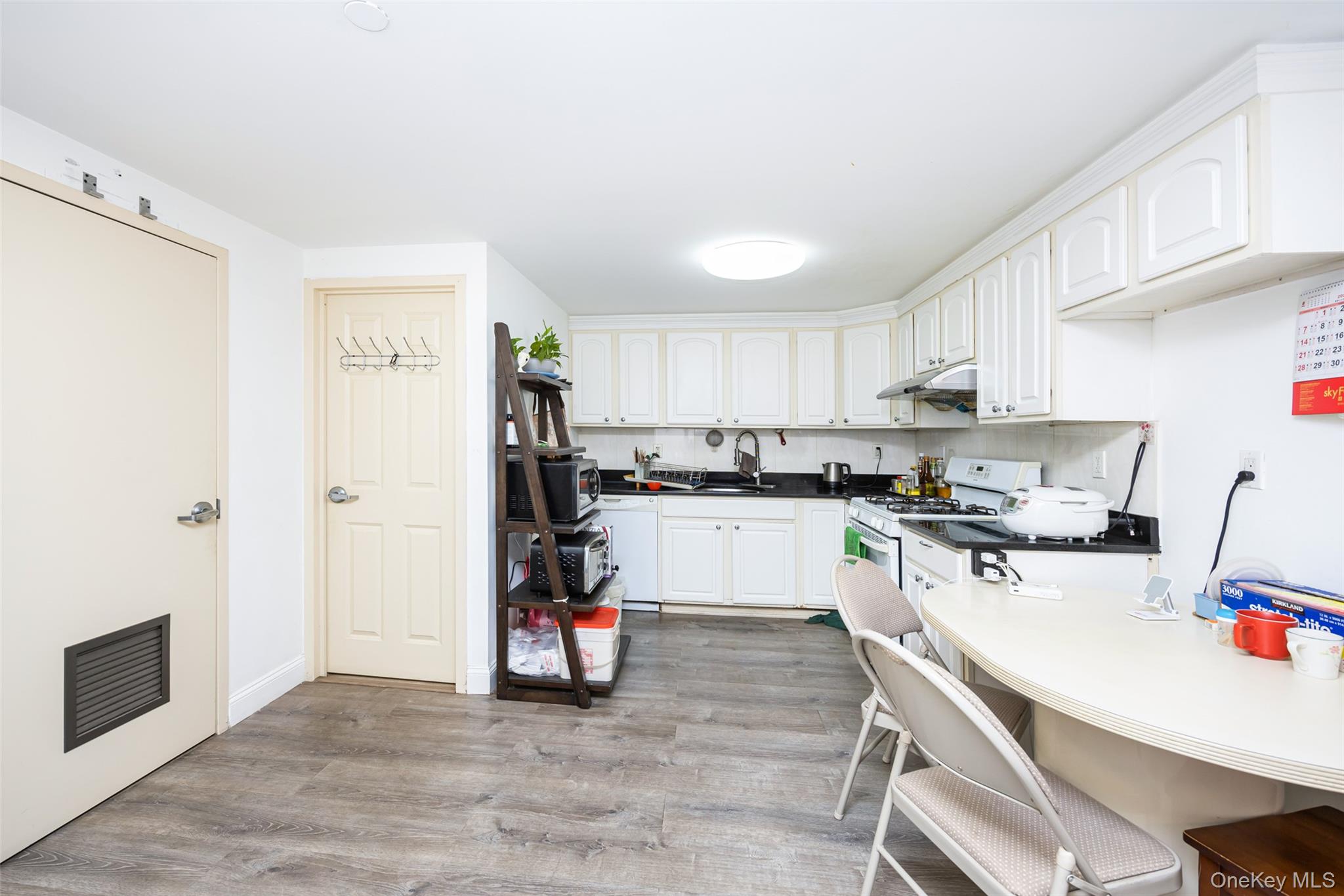 43-17 Union Street, Unit 4E Queens, NY 11355 - Photo 10 of 19 Kitchen featuring dark countertops, light wood-style floors, white cabinets, white appliances, and backsplash