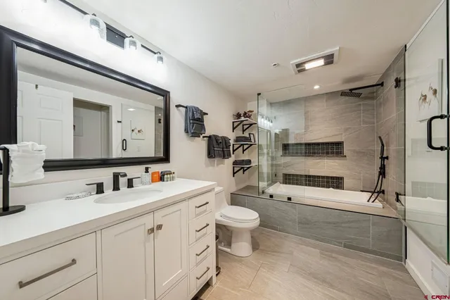 a bathroom with a double vanity sink toilet mirror and shower