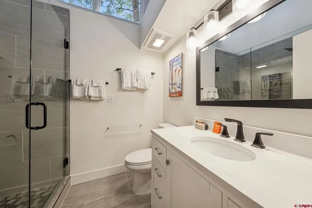 a bathroom with a granite countertop sink a toilet and shower