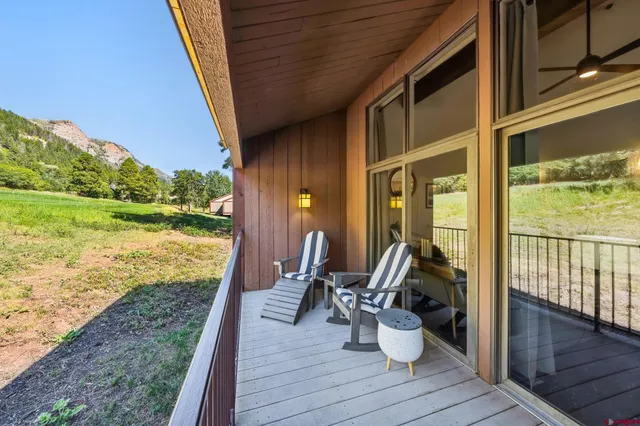 a view of two chairs and table in patio next to a yard