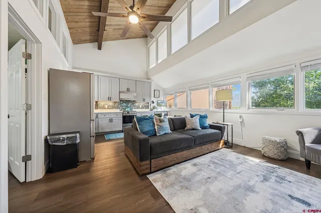 a living room with couches and kitchen view with wooden floor