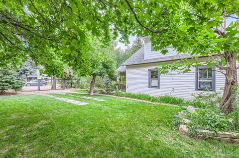 a backyard of a house with plants and large tree
