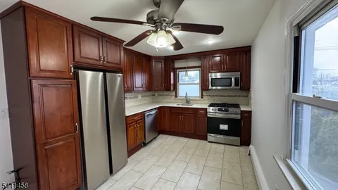 a kitchen with stainless steel appliances granite countertop a refrigerator a sink dishwasher a stove and a refrigerator with wooden floor