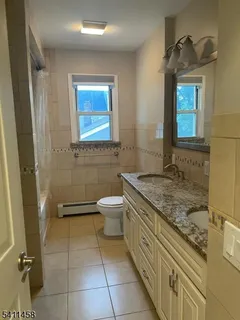 a bathroom with a granite countertop sink a toilet and a mirror