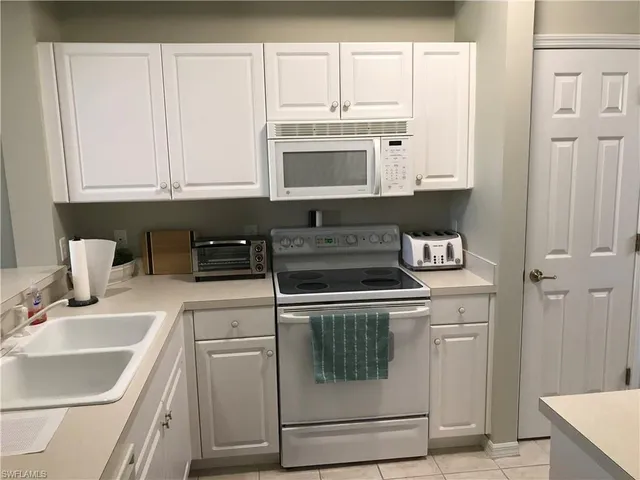 a kitchen with white cabinets and white appliances