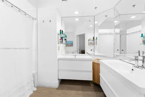 a bathroom with a double vanity sink a mirror and a bathtub