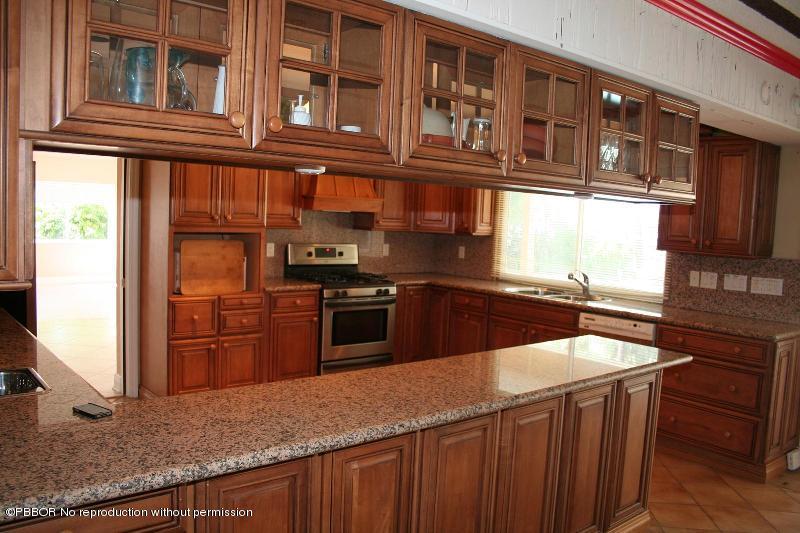 1515 Lands End Road Manalapan, FL 33462 - Photo 9 of 21 a kitchen with stainless steel appliances granite countertop a refrigerator a stove and a sink with wooden cabinets