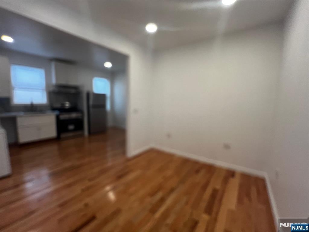 3 Montclair Avenue, Unit 2 Paterson, NJ 07503 - Photo 9 of 24 an empty room with wooden floor kitchen view and windows