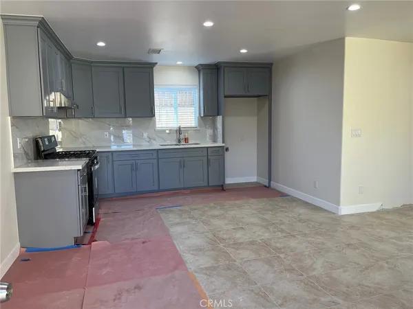 a kitchen with kitchen island granite countertop a sink stove and cabinets