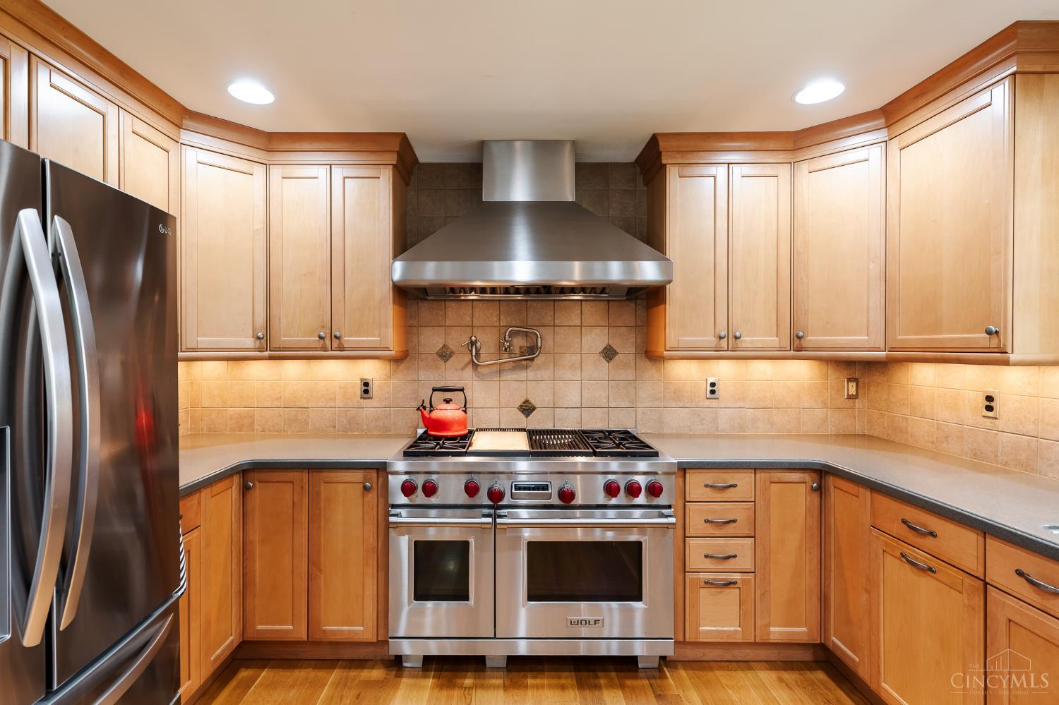 623 Ibold Road Loveland, OH 45140 - Photo 13 of 35 Designed with the home chef in mind, this exceptional kitchen offers custom cabinetry, expansive countertops, a large center island with seating, stainless steel appliances and a striking 48" Wolf professional range with double ovens, four burners, a built-in griddle and a commercial-style vent hood. The open-concept layout flows effortlessly into the dining area and great room, making it ideal for entertaining.