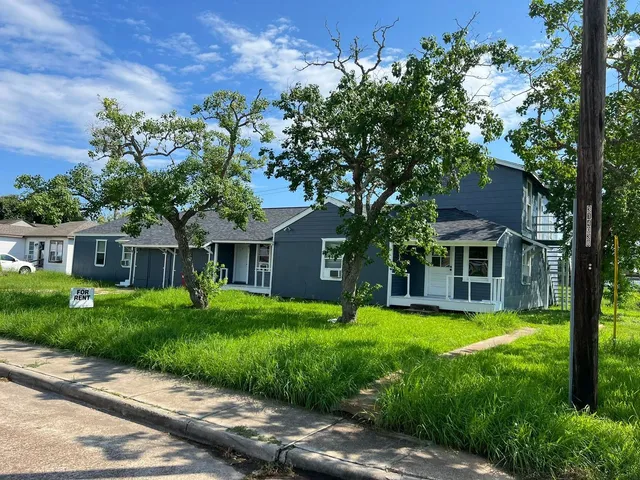 a front view of a house with a garden and trees