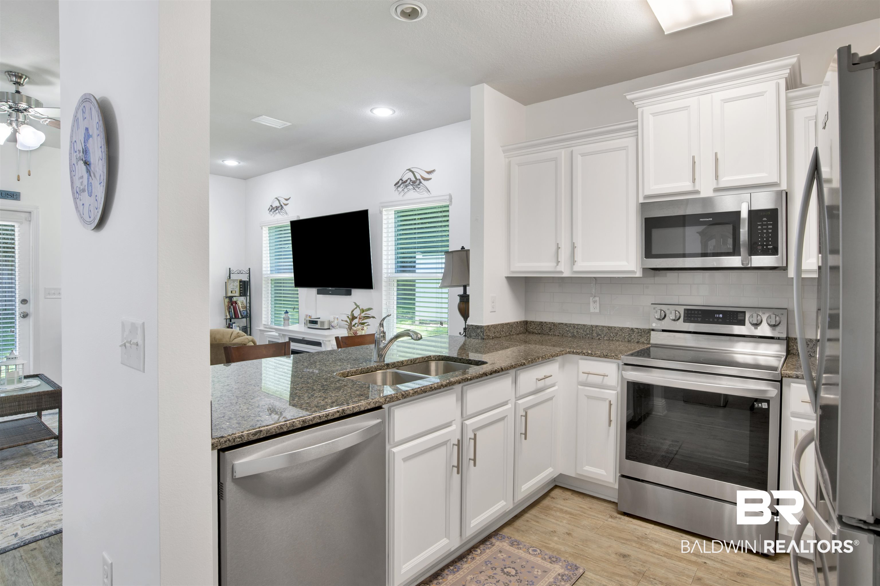 25806 Pollard Road, Unit 20 Daphne, AL 36526 - Photo 6 of 29 Kitchen with appliances with stainless steel finishes, sink, light wood-type flooring, dark stone countertops, and ceiling fan
