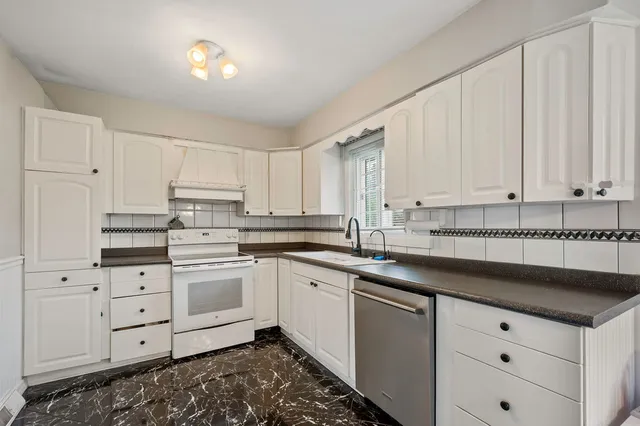 a kitchen with granite countertop white cabinets and white appliances
