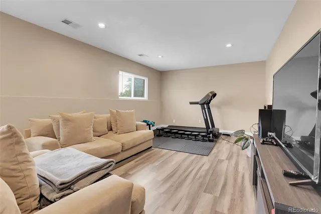 a living room with furniture a flat screen tv and a wooden floor