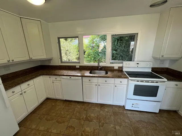 a kitchen with granite countertop white cabinets and white appliances
