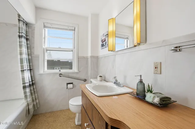 a bathroom with a granite countertop sink toilet and a window