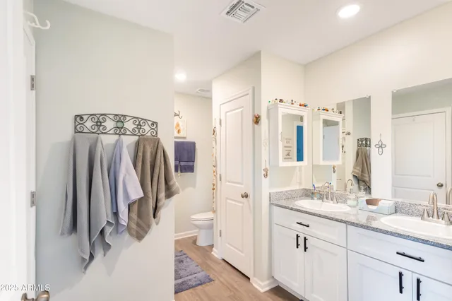 a bathroom with a double vanity sink a mirror a toilet and a shower