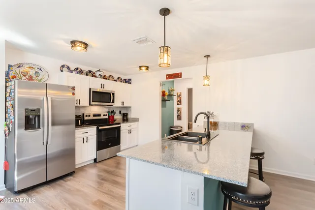 a kitchen with granite countertop a sink cabinets and stainless steel appliances