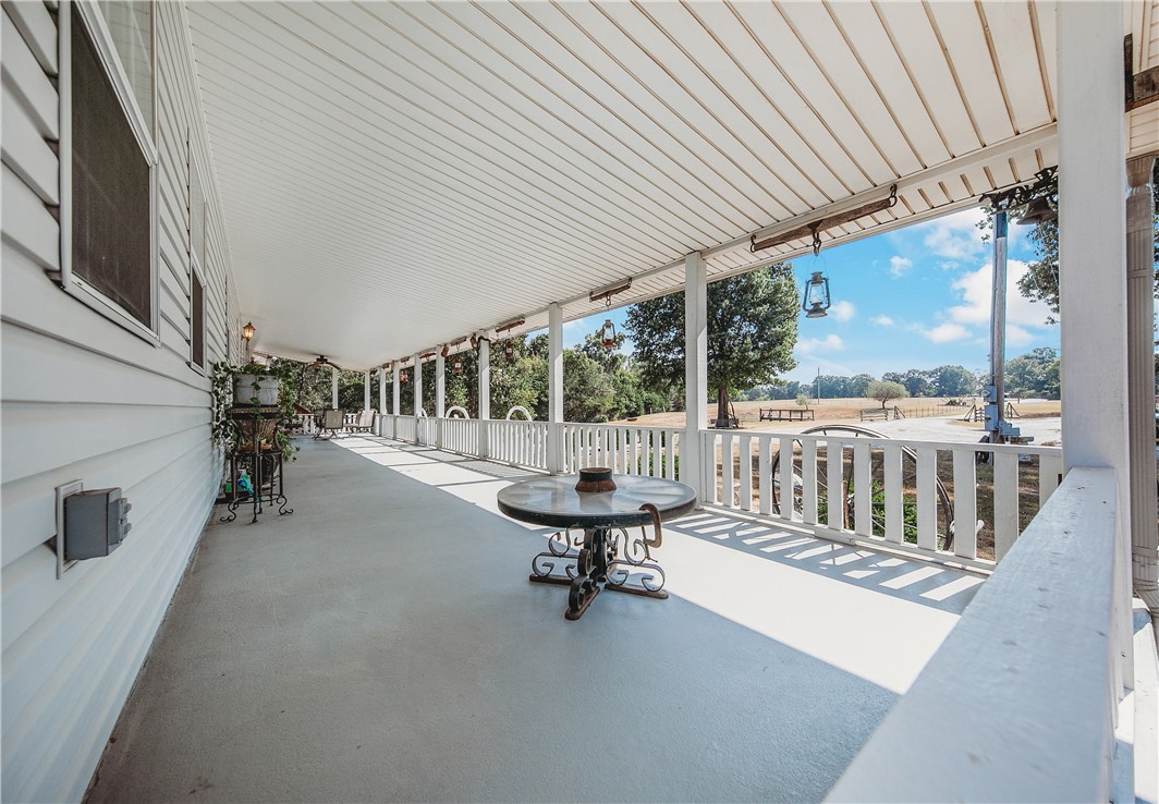 21587 West Hickory Flat Road Springdale, AR 72764 - Photo 9 of 45 Expansive covered front porch overlooking the peaceful acreage—an inviting place to relax and enjoy the rural setting.