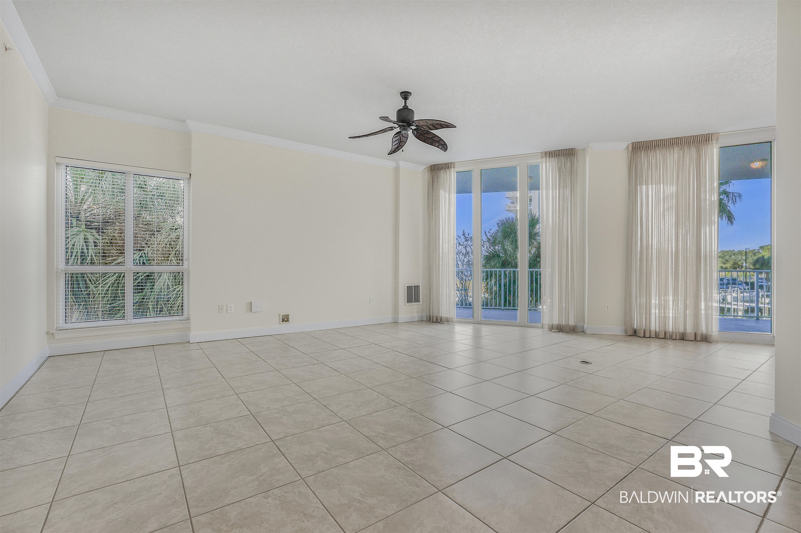 28250 Canal Road, Unit 106 Orange Beach, AL 36561 - Photo 7 of 50 Spare room with ornamental molding, healthy amount of natural light, expansive windows, a ceiling fan, and light tile patterned floors