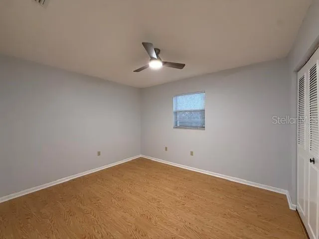 an empty room with a fan & a window
