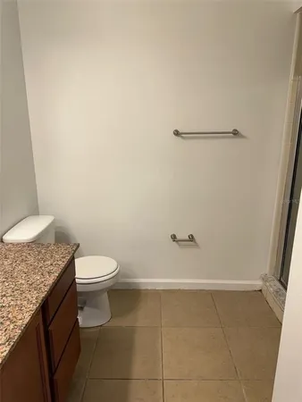a bathroom with a granite countertop toilet and a rug