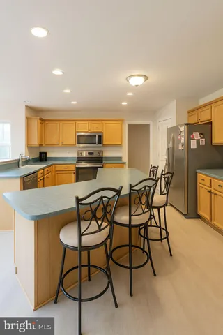 a kitchen with stainless steel appliances granite countertop a stove top oven a dining table and chairs with wooden floor