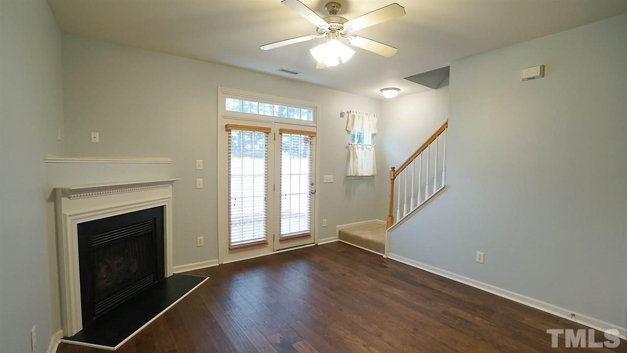 8311 Martello Lane Raleigh, NC 27613 - Photo 14 of 30 wooden floor in an empty room with a fireplace and a window