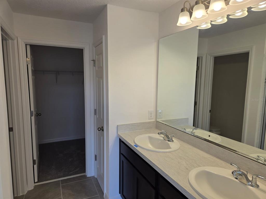 4827 Noble Cypress Street Kissimmee, FL 34746 - Photo 26 of 29 a bathroom with a granite countertop sink and a mirror