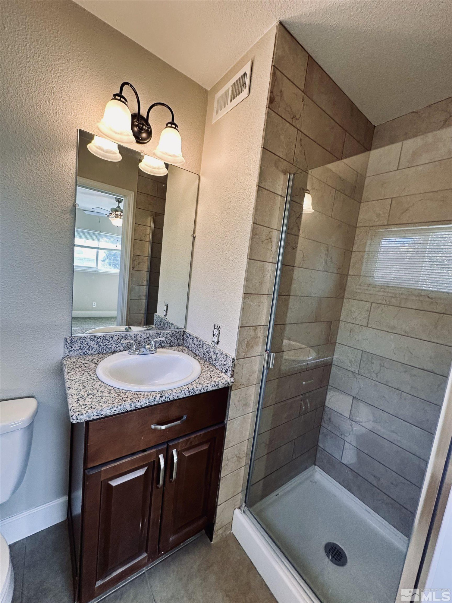 1945 Gridley Avenue Reno, NV 89503 - Photo 20 of 27 a bathroom with a granite countertop sink a toilet a mirror and shower