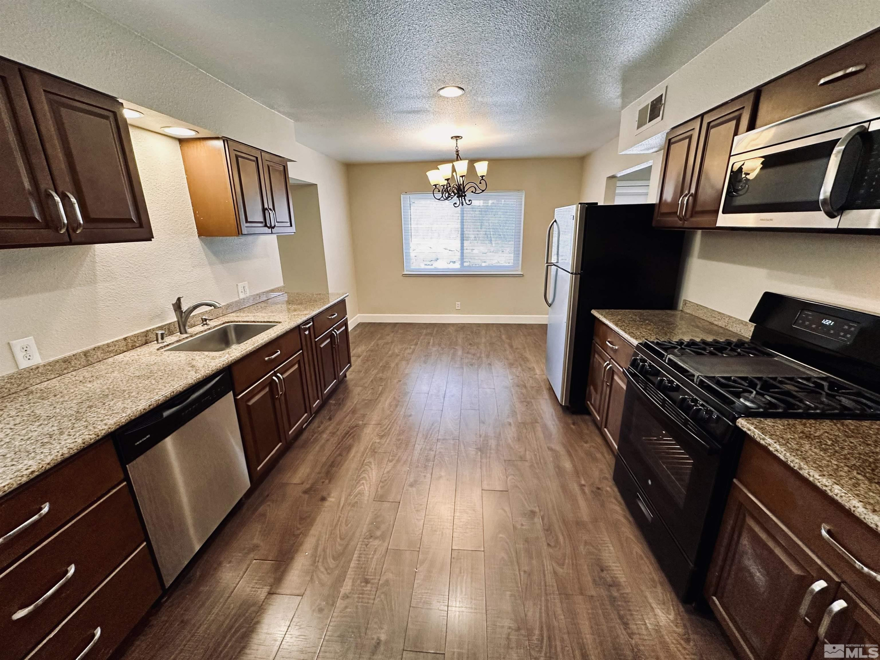 1945 Gridley Avenue Reno, NV 89503 - Photo 8 of 27 a kitchen with granite countertop wooden floors and black appliances